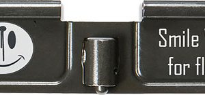 Close-up of a camera flash unit with a smiley icon and the text 'Smile Wait for flash'.