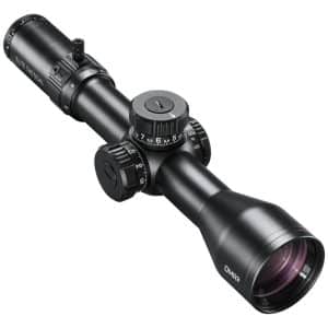 Black tactical riflescope with multiple adjustment dials and a large objective lens, mounted in the center of the image about at an angle.
