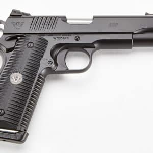 Close-up of a dark gray semi-automatic pistol shown from the left side, highlighting the slide, grip, trigger, and muzzle area (Wilson Combat ACP).