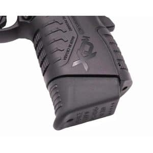 Close-up of a black handgun grip with textured surface and part of the magazine base plate visible.