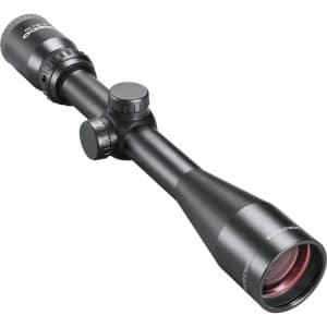 Black riflescope with adjustment turrets and large front lens viewed from an angled side, showing its mount-ready body