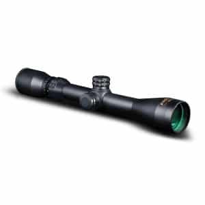 Black rifle scope with adjustment knobs and a green-tinted objective lens on a white background.