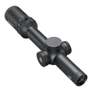 Black rifle scope with knurled adjustment dials and objective lens, photographed at an angle.